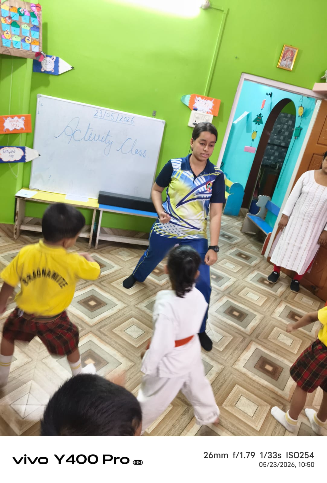 Caring teacher with young students in a classroom at Buds & Blossoms